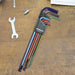 Set of different coloured long hex keys in a Bondhus case on a wooden surface with a wrench and Allen key.