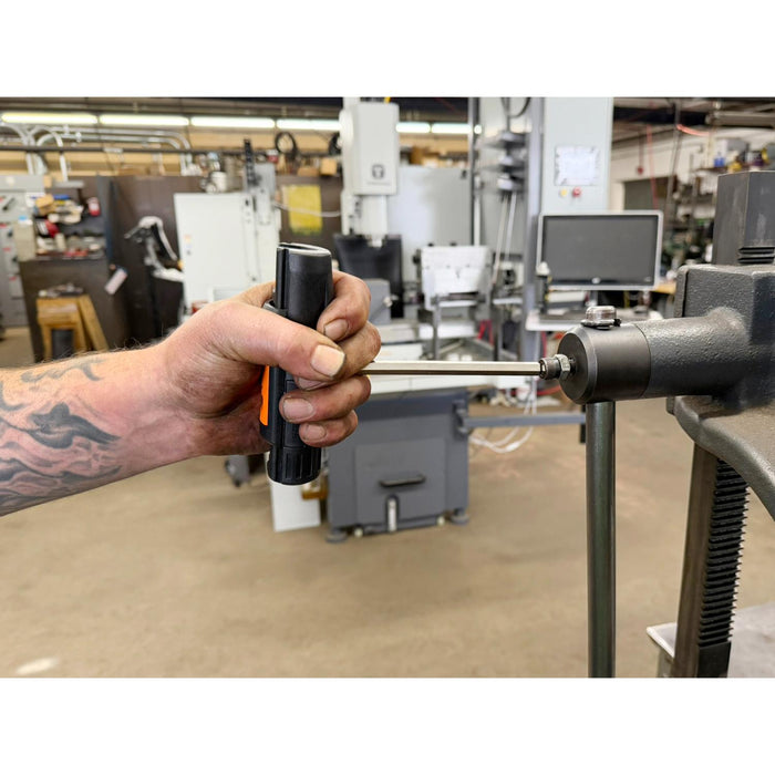 Hand holding a tool near industrial equipment in a workshop setting