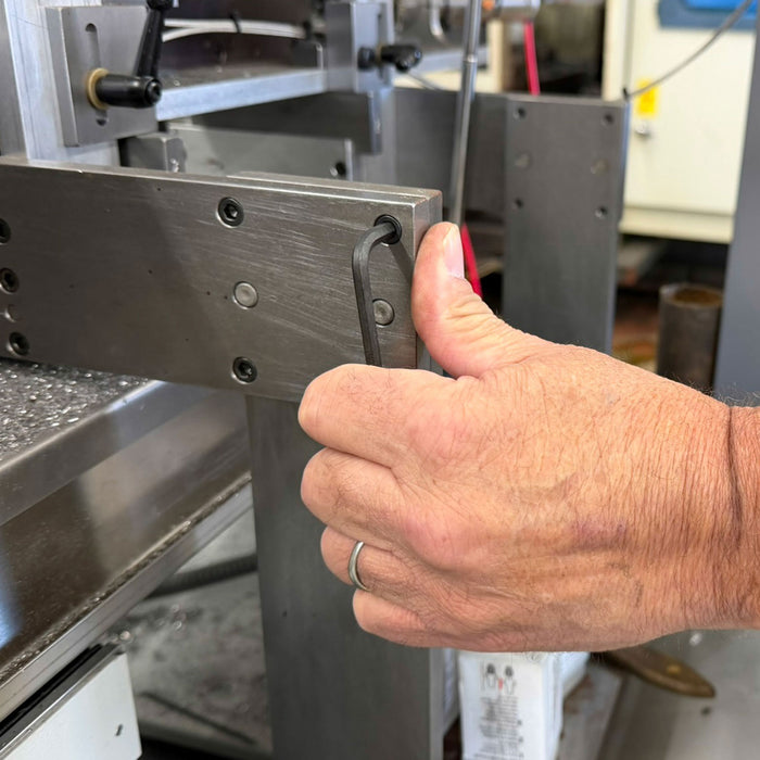 Hand adjusting a metal component on a machine in an industrial setting
