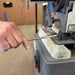 Hand using a metal file on a bench vice in a workshop setting