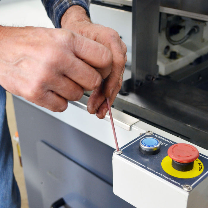 Person using a hex key on a machine control panel