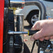 Hand using a Nut driver on a mechanical component with a blurred vehicle in the background