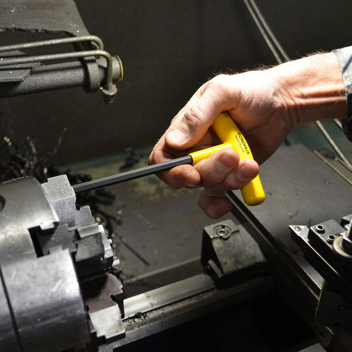 Hand using a yellow t handle tool on a mechanical component