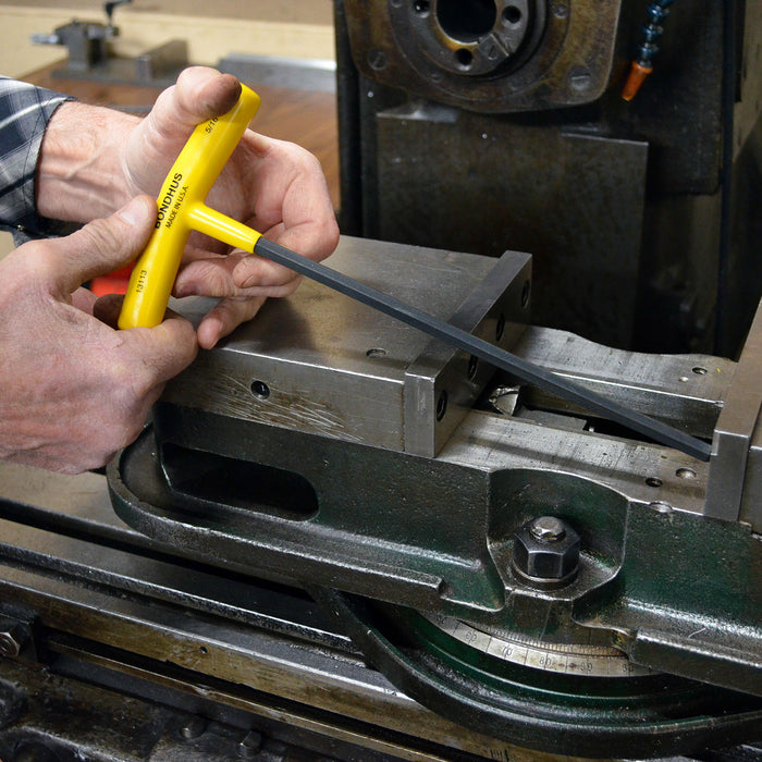 Person using a yellow tool on a metal machine part