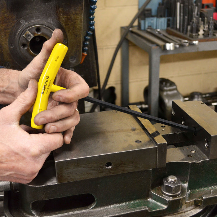 Person using a yellow tool on a metal surface in a workshop setting