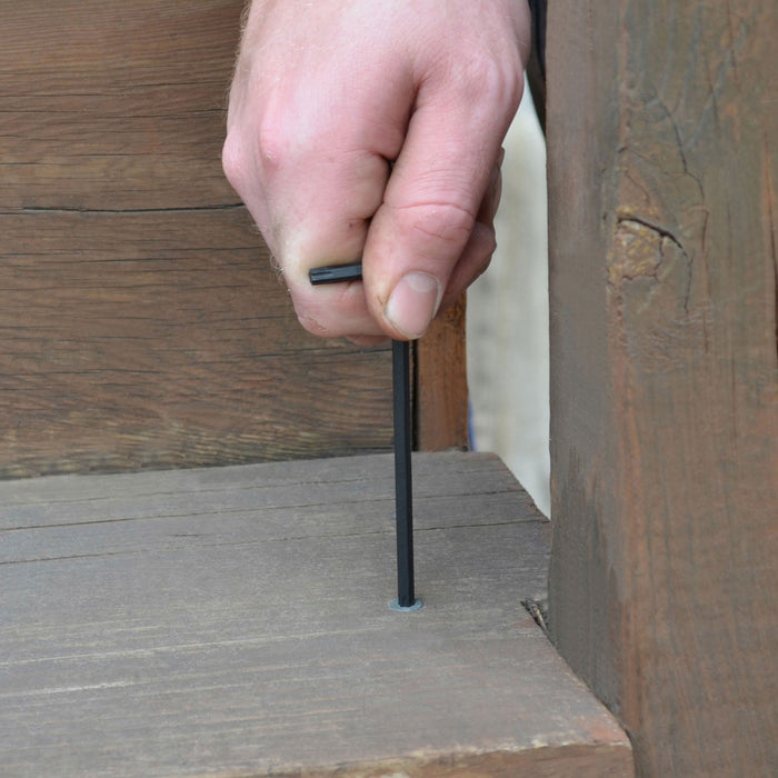 Hand using a black L Wrench to tighten bolt on wooden step
