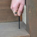 Hand using a black L Wrench to tighten bolt on wooden step
