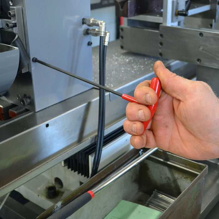 Hand using a red screwdriver on a machine.