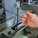 Hand using a red screwdriver on a machine.