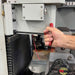 Hand using a red tool on a machine with a focus on the action of adjusting or operating the equipment.