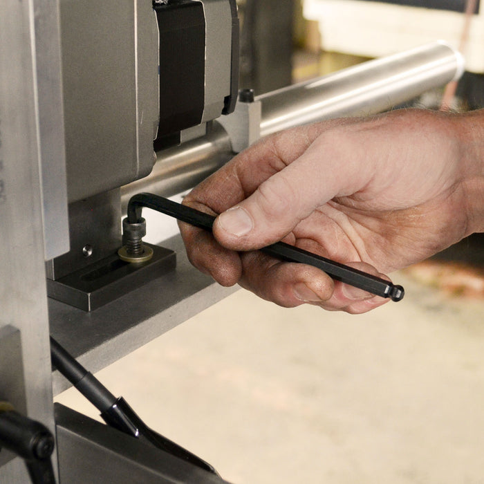 Hand adjusting a tool on a machine, likely in a workshop setting