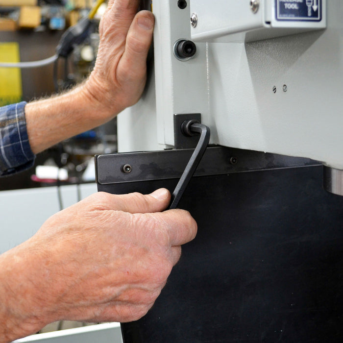 Person using a tool on a machine in a workshop setting
