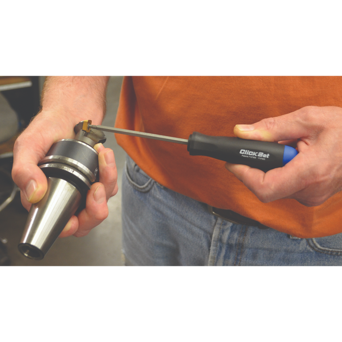 Person wearing an orange T-shirt and jeans using a click set screwdriver to tighten a tool in a workshop