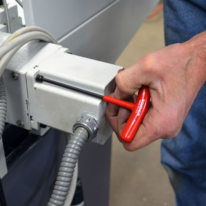 Person using a red tool on a machine component
