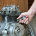 Hand holding a screwdriver near a motorcycle engine