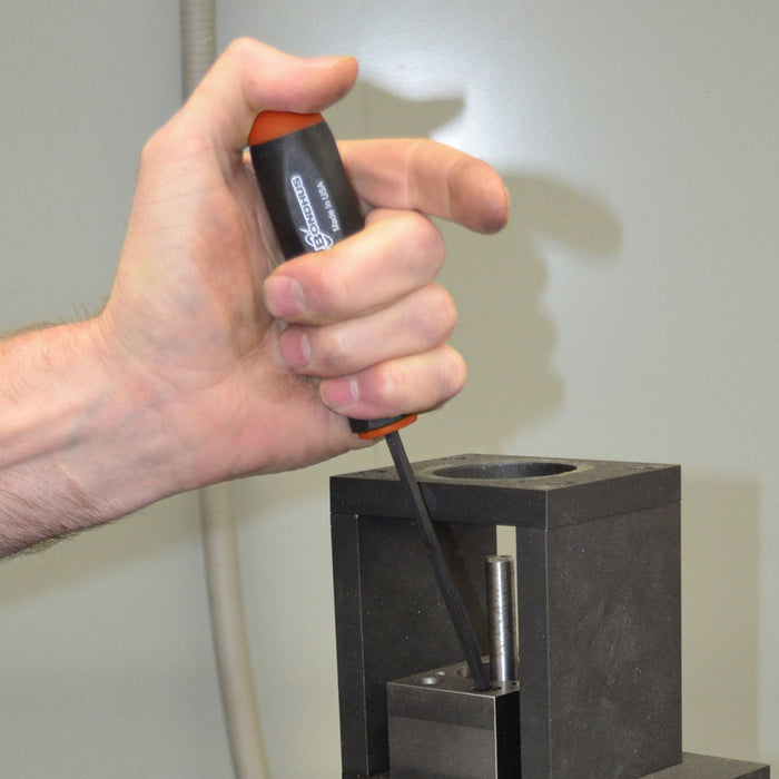 Hand using a screwdriver to work on a metal component against a neutral background